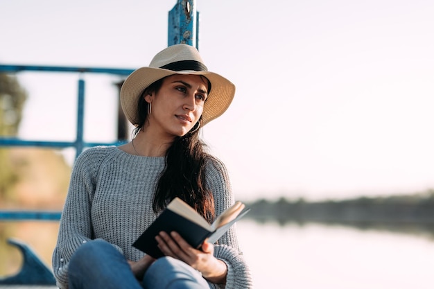 Primo piano di una giovane donna che si rilassa e legge un libro mentre è seduto su un molo Tempo di relax per sfuggire alla routine