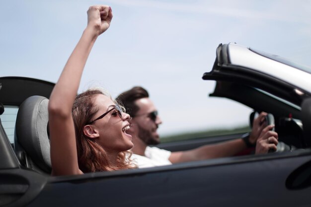 Primo piano di una giovane donna con il suo ragazzo in un'auto decappottabile