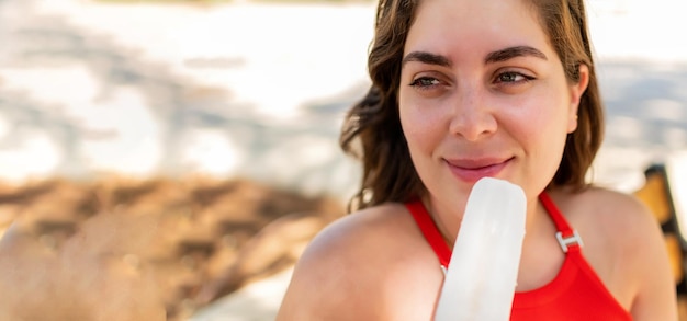 Primo piano di una giovane donna sorridente che tiene un ghiacciolo al parco