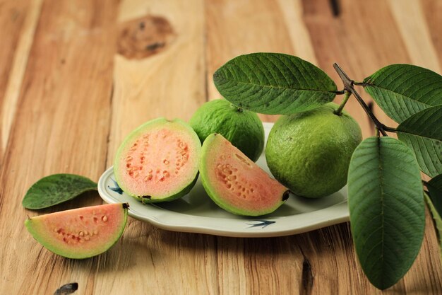 Primo piano di una guava rossa rosa tagliata a metà, fresca raccolta, sulla tavola di legno