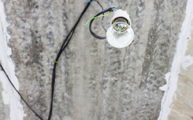 Primo piano di una lampadina appesa in una vista dal basso di una stanza vuota