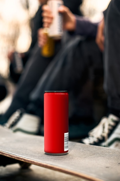 Primo piano di una lattina di alluminio rosso con un drink, su uno skateboard nel parco.