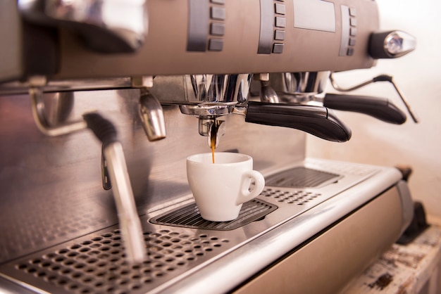 Primo piano di una macchina per caffè espresso che produce una tazza di caffè.