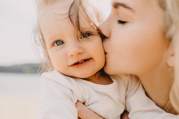 Primo piano di una madre che bacia la sua piccola figlia sulla guancia