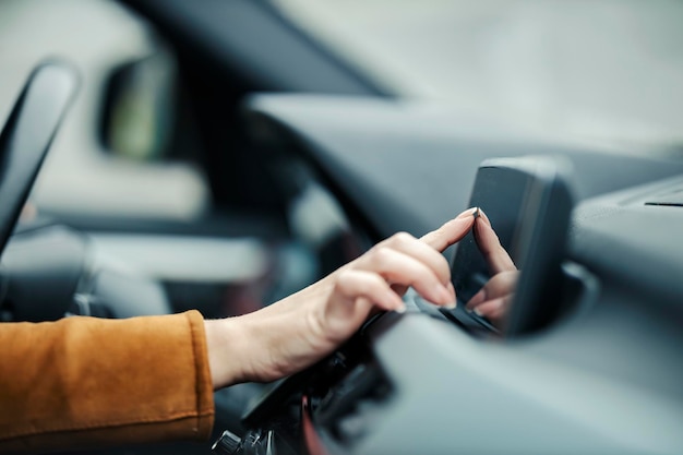 Primo piano di una mano femminile che inserisce le coordinate sul gps in auto