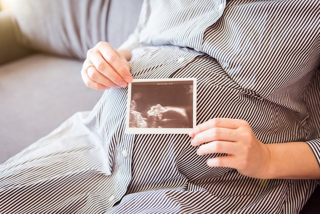 Primo piano di una pancia incinta con foto ad ultrasuoni