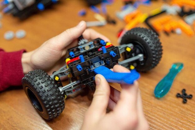 Primo piano di una parte dell'auto nelle mani di un ragazzo Kid fa un'auto utilizzando parti del set di costruttori di meccanica ingegneristica