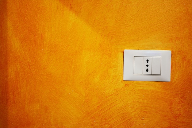 Primo piano di una presa in una parete arancione
