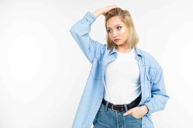 Primo piano di una ragazza attraente sexy in una camicia di jeans blu e maglietta bianca in posa su uno studio bianco