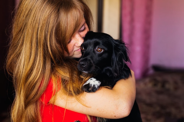 Primo piano di una ragazza che abbraccia un cagnolino nero