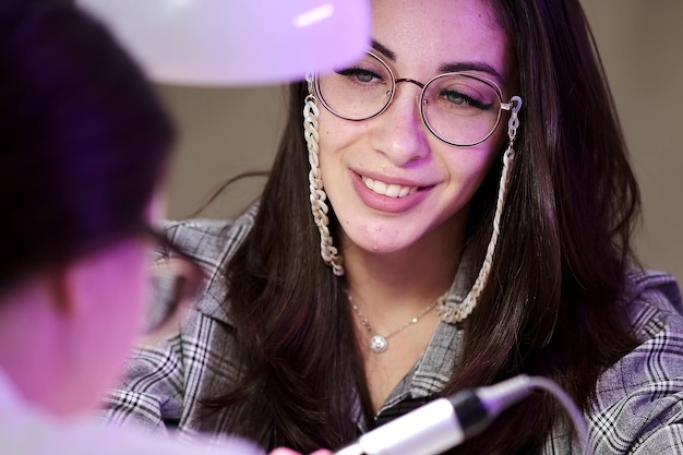 Primo piano di una ragazza che fa una manicure in un salone di bellezza Il cliente sorride e gode del processo di manicure Cura delle unghie Procedura cosmetica