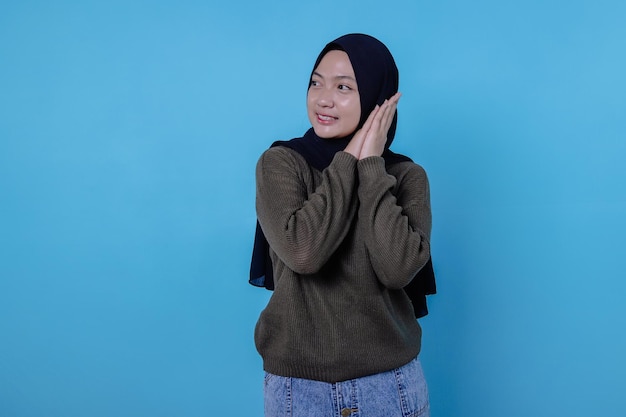 Primo piano di una ragazza felice che indossa l'hijab in un panno casual e sorride sulla parete blu