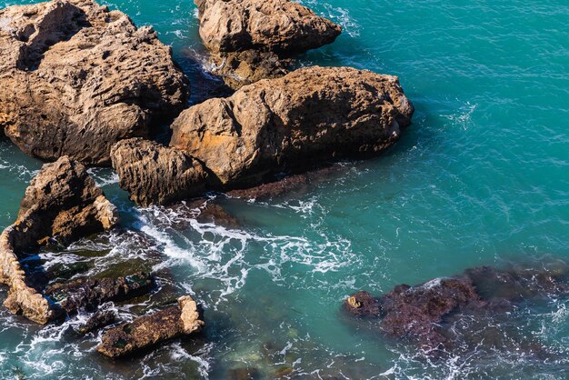 Primo piano di una ripida roccia tagliente con vegetazione sullo sfondo del mare