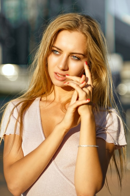 Primo piano di una seducente donna bionda con una pelle perfetta e un trucco nudo in posa sul viale