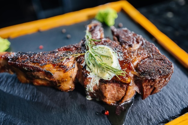 Primo piano di una succosa bistecca alla griglia con burro e condimenti. Carne alla griglia in un ristorante.