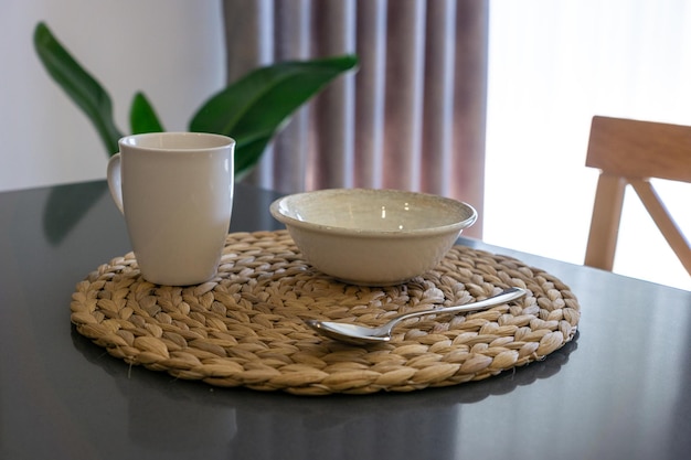 Primo piano di una tazza con il cucchiaio e la ciotola per la colazione preparata sul tavolo