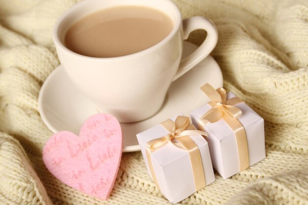 Primo piano di una tazza di caffè con piccoli contenitori di regalo e cuori