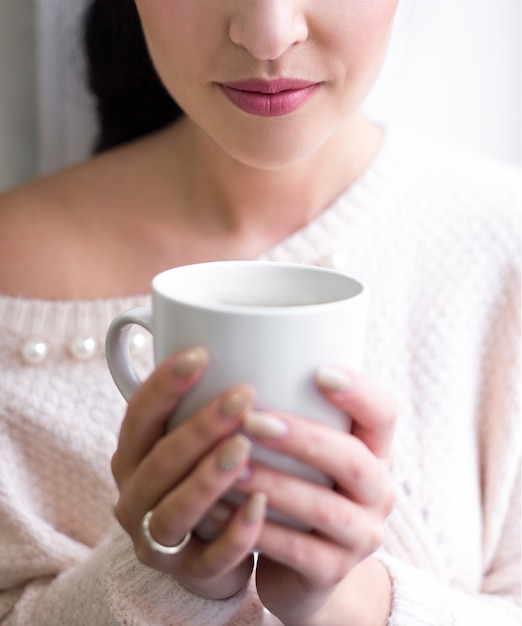 Primo piano di una tazza di caffè in mani femminili