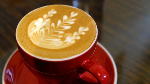 Primo piano di una tazza di cappuccino con una bella arte del caffè su un piattino rosso