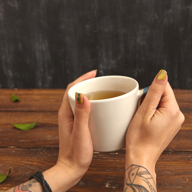 Primo piano di una tazza di tè verde profumato in mani femminili