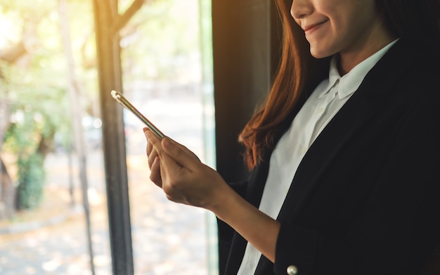 Primo piano di una tenuta della donna di affari e di un telefono cellulare usando all'interno