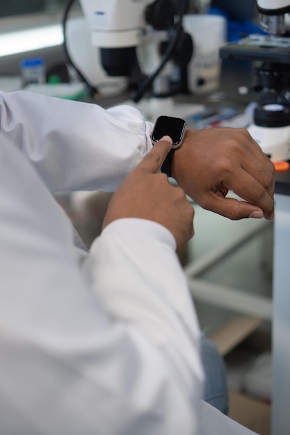 Primo piano di uno scienziato che utilizza uno smartwatch in laboratorio