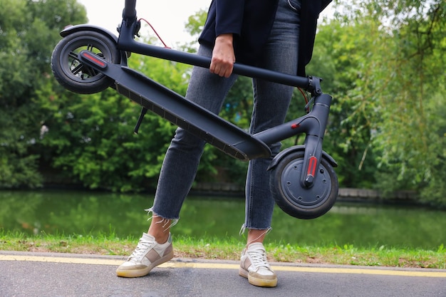 Primo piano di uno scooter elettrico nelle mani di una donna Una persona irriconoscibile Vendita di scooter elettrici