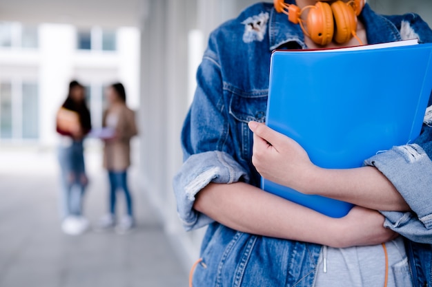 Primo piano di uno studente di college che tiene le cartelle mentre si trovava al concetto di educazione del corridoio