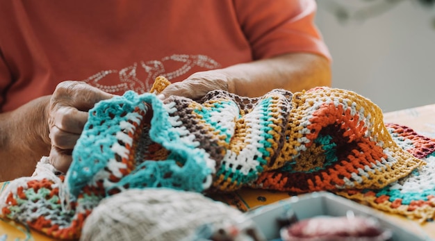 Primo piano di vecchie mani di donna matura che lavorano con uncinetto e filo per cucire Stile di vita del concetto di attività per il tempo libero domestico al coperto Anziani Persone di sesso femminile anziane irriconoscibili nell'hobby vita attiva Gioventù invecchiante