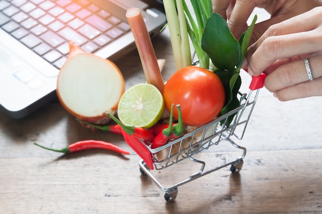 Primo piano di verdure fresche nel carrello della spesa con le mani della donna