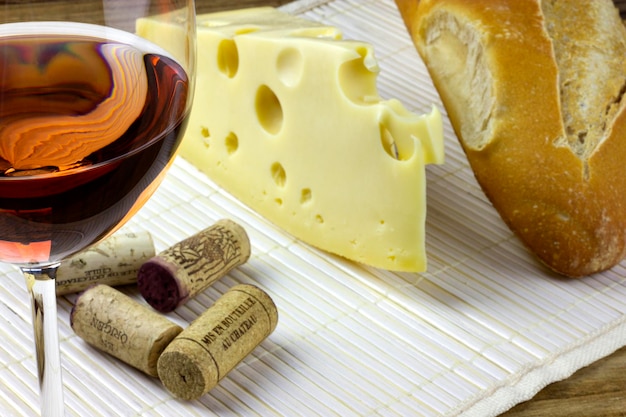 Primo piano di vino rosato in sughero formaggio e lode di pane italiano su tavola bianca gioco americano