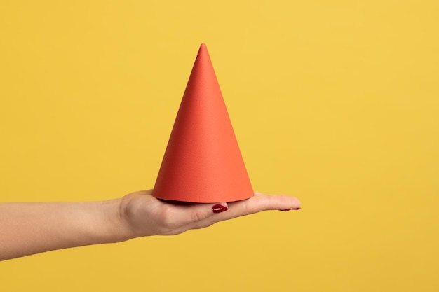 Primo piano di vista laterale del profilo della mano della donna che tiene il cono di compleanno rosso della palma che celebra l'evento