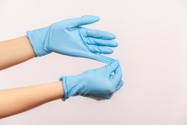 Primo piano di vista laterale di profilo della mano umana in guanti chirurgici blu che mostra come prendere dei guanti.