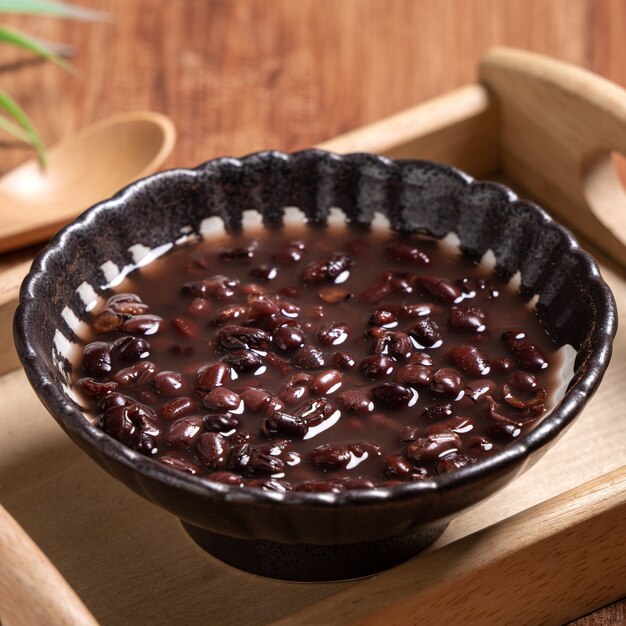 Primo piano di zuppa di fagioli rossi adzuki in una ciotola sul fondo della tavola in legno per mangiare.