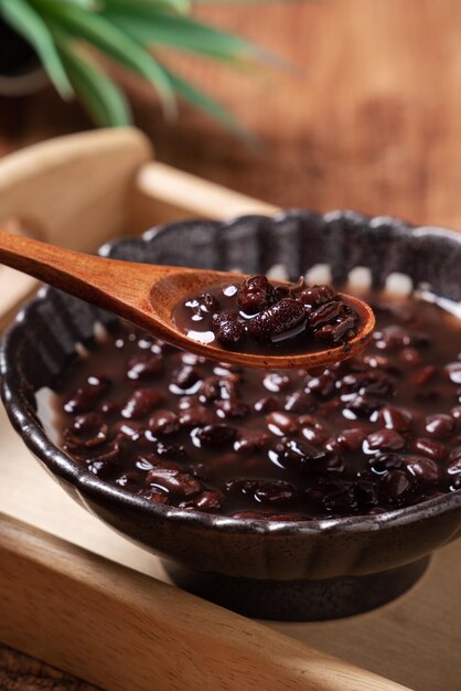 Primo piano di zuppa di fagioli rossi adzuki in una ciotola sul fondo della tavola in legno per mangiare.