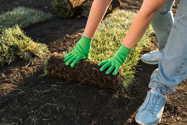 Primo piano donna che posa zolla per il nuovo concetto di posa di erba erbosa da giardino