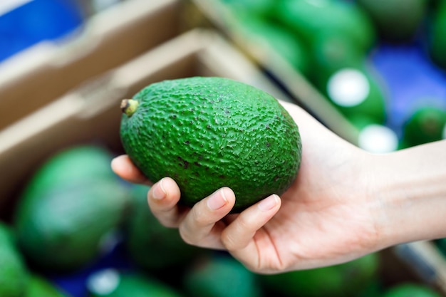 Primo piano Donna che sceglie gli avocado verdi hass al supermercato