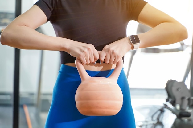 Primo piano e raccolto giovane allenamento femminile con peso kettlebell nel centro fitness