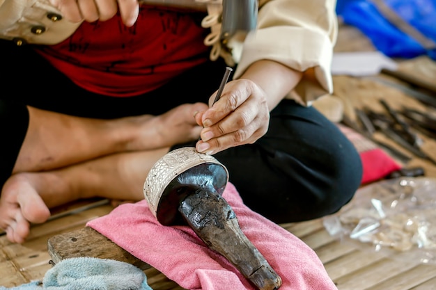 Primo piano e raccolto Mani di dimostrazione Thailander di ciotola d'acqua d'argento scolpita a Chiang Mai, Thailandia.