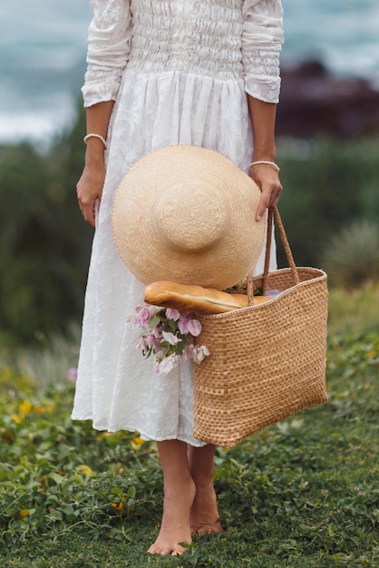 Primo piano elegante donna bohémien con borsa da spiaggia e cappello di paglia pronto per il picnic