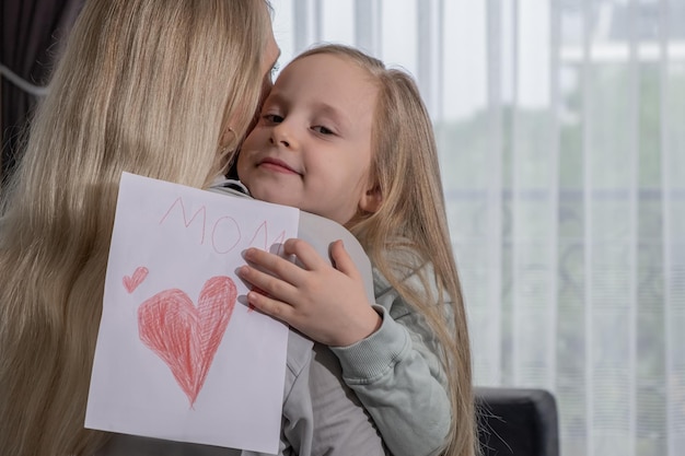 Primo piano figlia ritratto che saluta sua madre con la festa della mamma e dà carta fatta a mano e abbracci