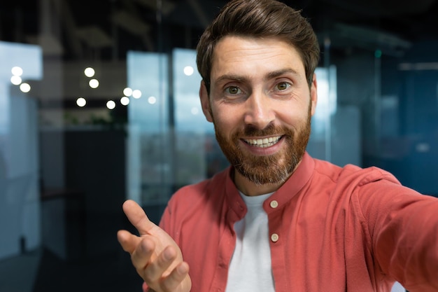 Primo piano foto giovane uomo d'affari freelance blogger in una camicia rossa in ufficio a parlare su un video