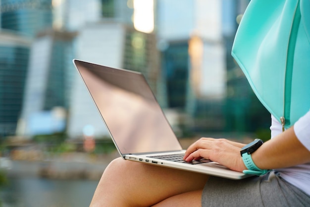 Primo piano foto ritagliata di donna d'affari seduta con laptop all'aperto