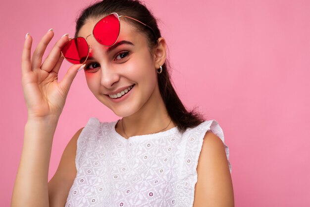 Primo piano fotografico di una bella giovane donna bruna positiva che indossa abiti casual estivi e occhiali da sole eleganti stylish