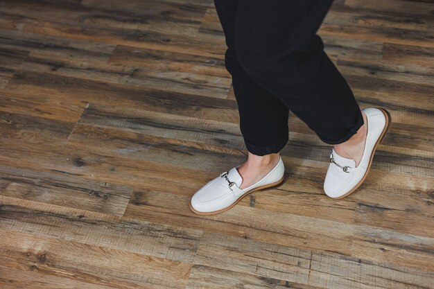 Primo piano gambe femminili in pantaloni neri e mocassini beige in pelle Nuova collezione primavera estate di scarpe da donna in pelle 2022