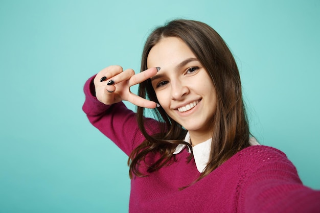 Primo piano giovane donna bruna ragazza in abiti casual in posa facendo selfie girato sul telefono cellulare isolato su sfondo blu ritratto in studio. Persone sincere emozioni concetto di stile di vita. Mock up spazio di copia