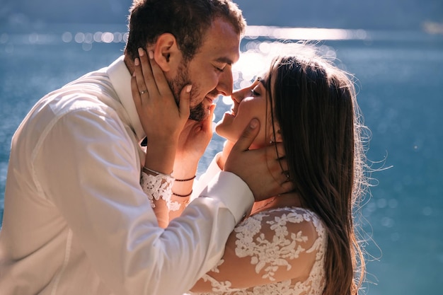 Primo piano Gli sposi si baciano sullo sfondo del lago e delle montagne Luogo del matrimonio