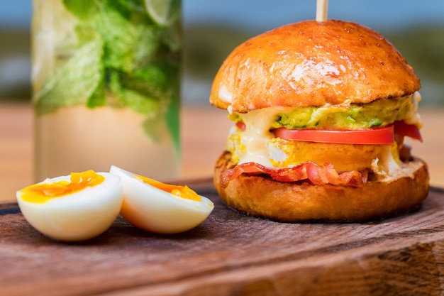 Primo piano hamburger alto e gustoso con pomodori al formaggio e frittata serviti su tavola da portata