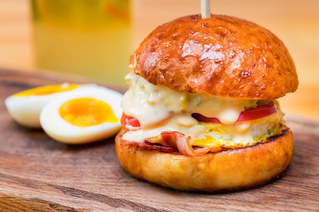 Primo piano hamburger alto e gustoso con pomodori al formaggio e frittata serviti su tavola da portata