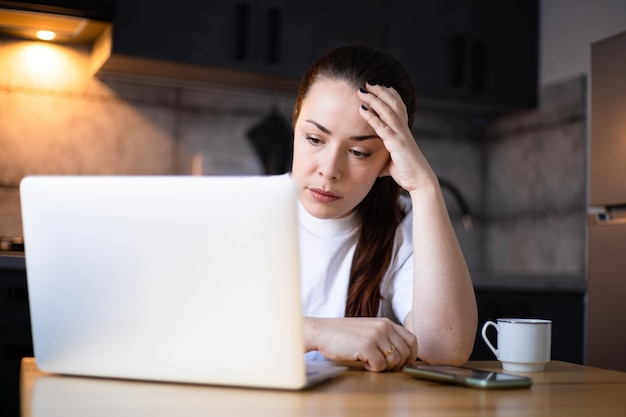 Primo piano infelice imprenditrice stressata che legge cattive notizie nella posta elettronica studente frustrato che lavora su un compito difficile progetto online Duro lavoro a distanza Lavoro in cucina ufficio